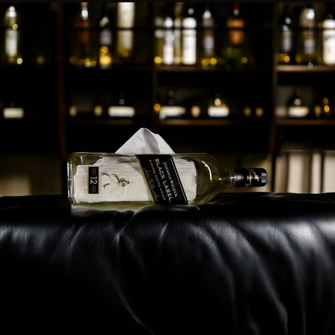 Bottle of Absolut Vodka on a black leather surface with blurred bar background